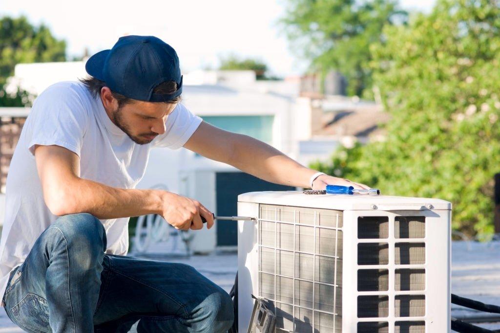 Air conditioner technician servicing mini-split heat pump on roof top
