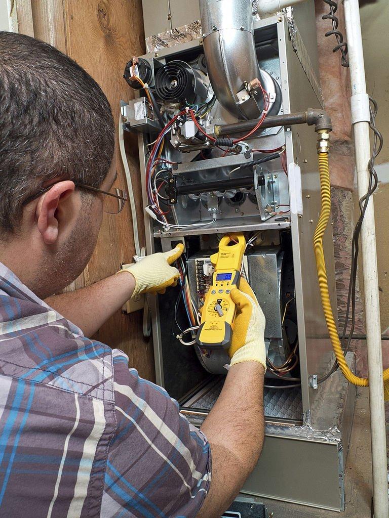Hispanic handyman repairman conducting residential HVAC repair