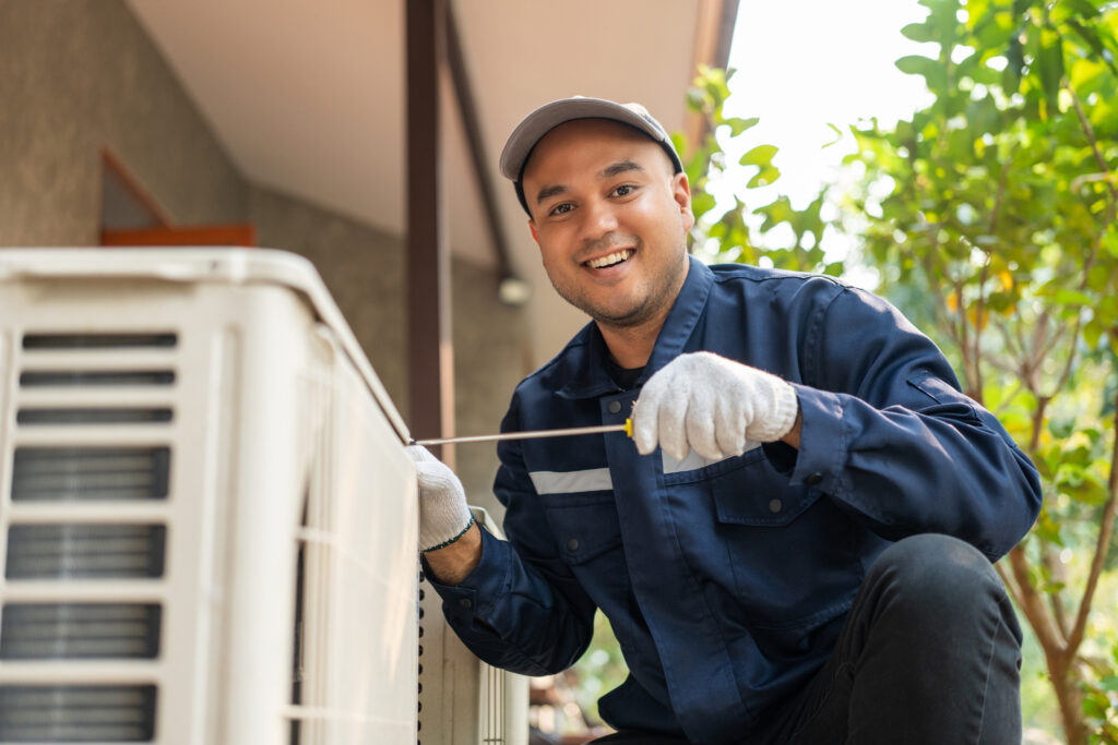 Technician smiling as he tunes up an outdoor AC system.
