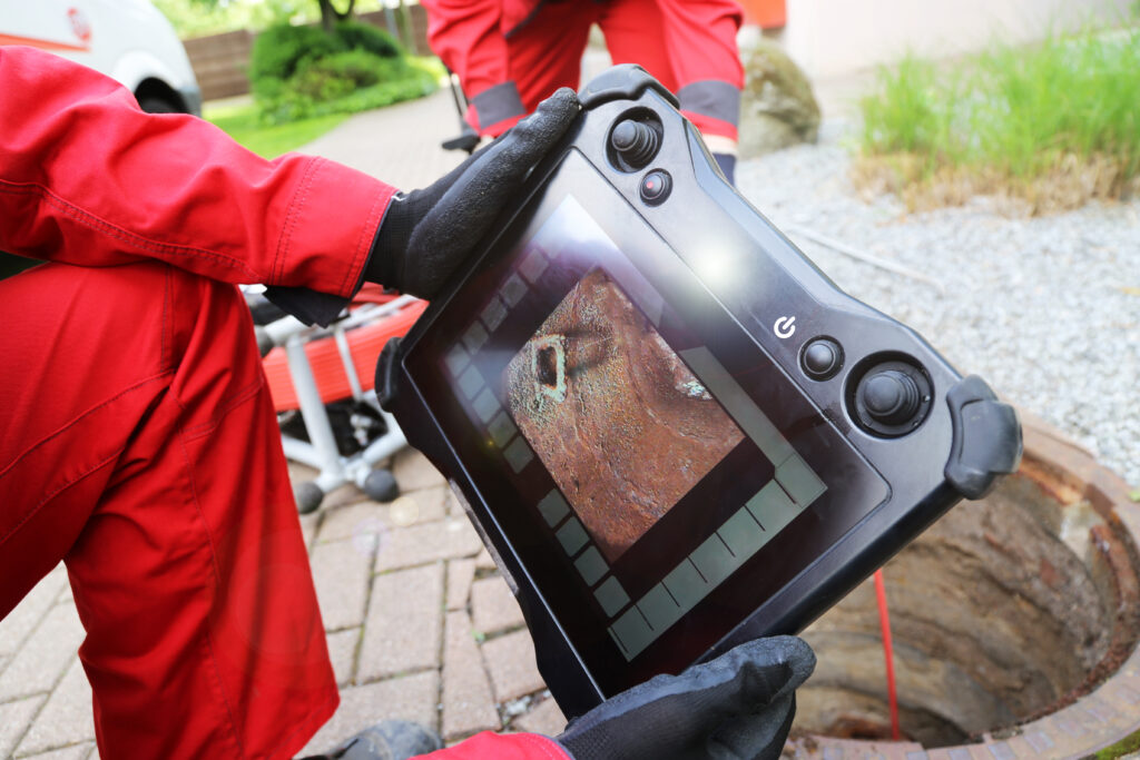 Plumber's hands holding a sewer inspection camera.